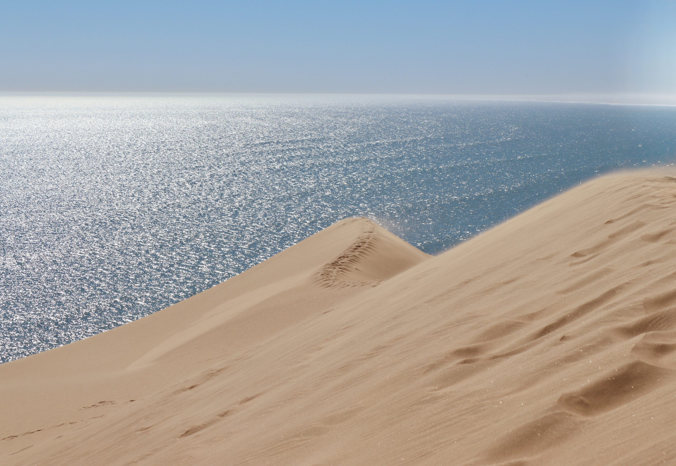 Picture of a sand dune and bright blue sky.