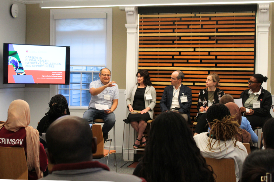 Panel of 5 individuals sitting at the front of the room speaking with an audience of students.
