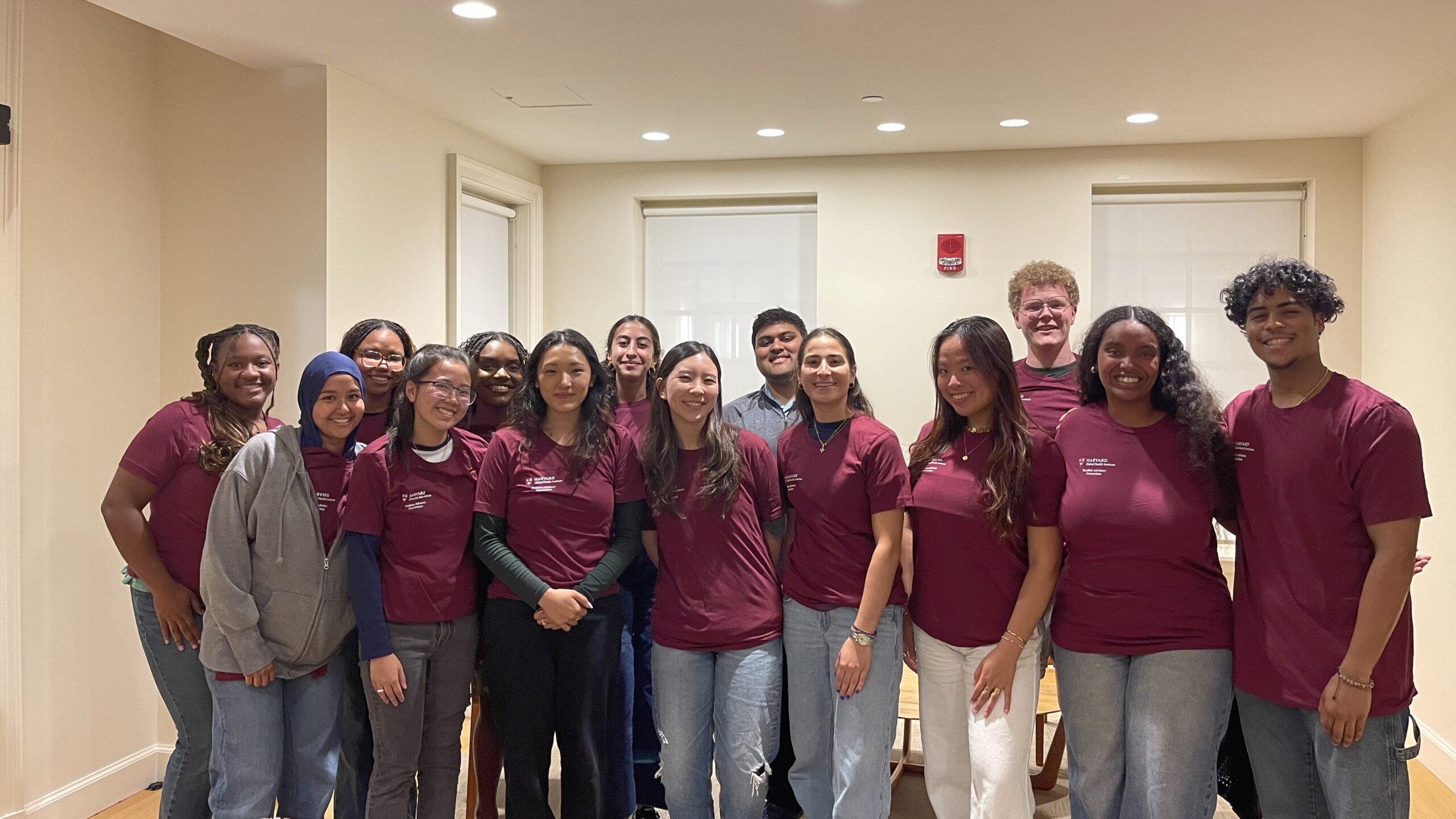 Group of Harvard Students standing smiling in matching shirts.