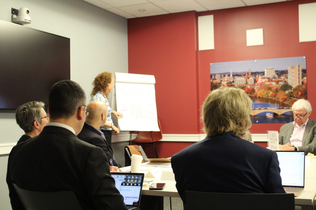 Margaret B. next to a whiteboard presenting to group sitting.