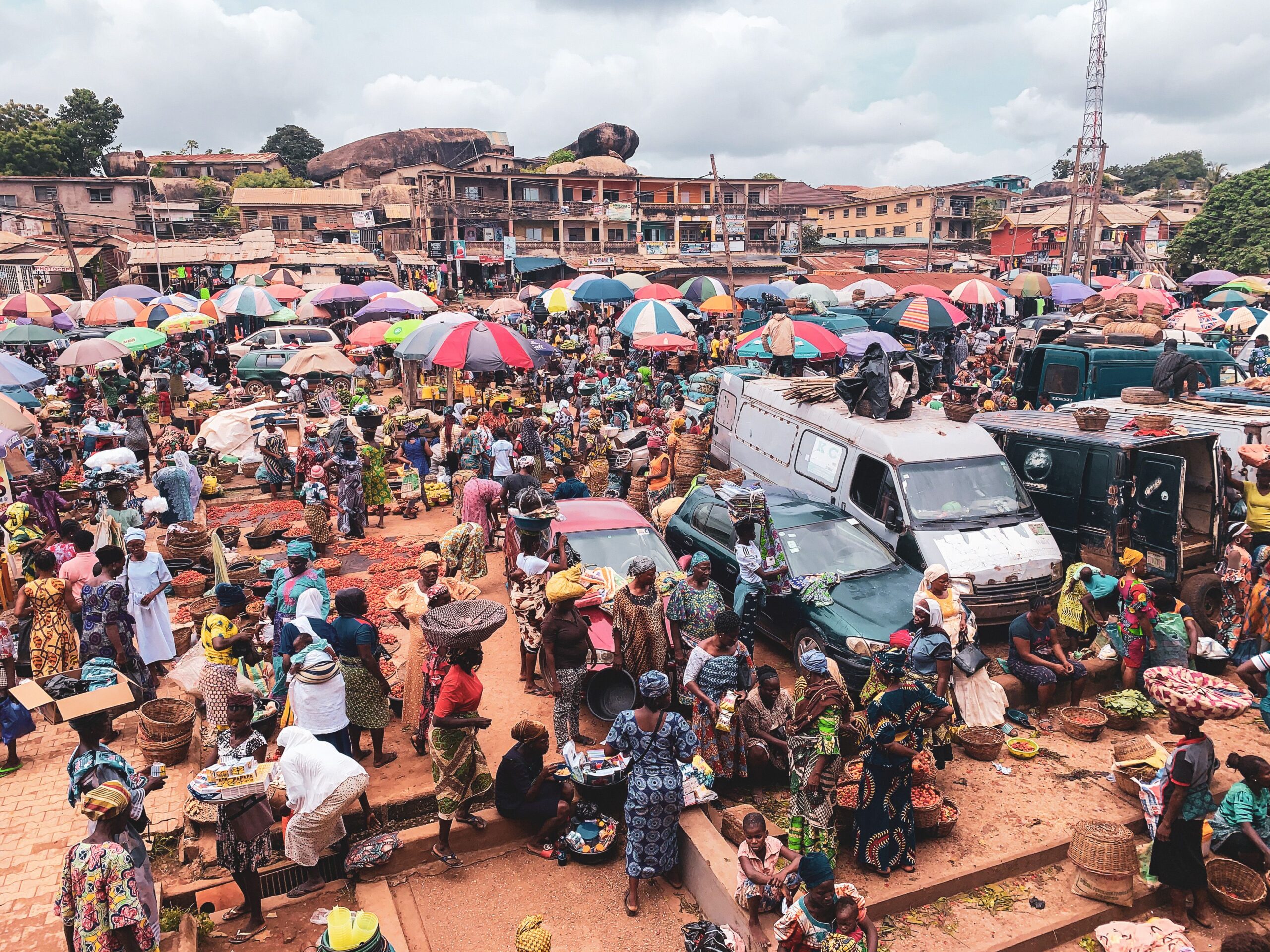 Bustling market scene with colorful umbrellas, merchants, and shoppers in an urban environment