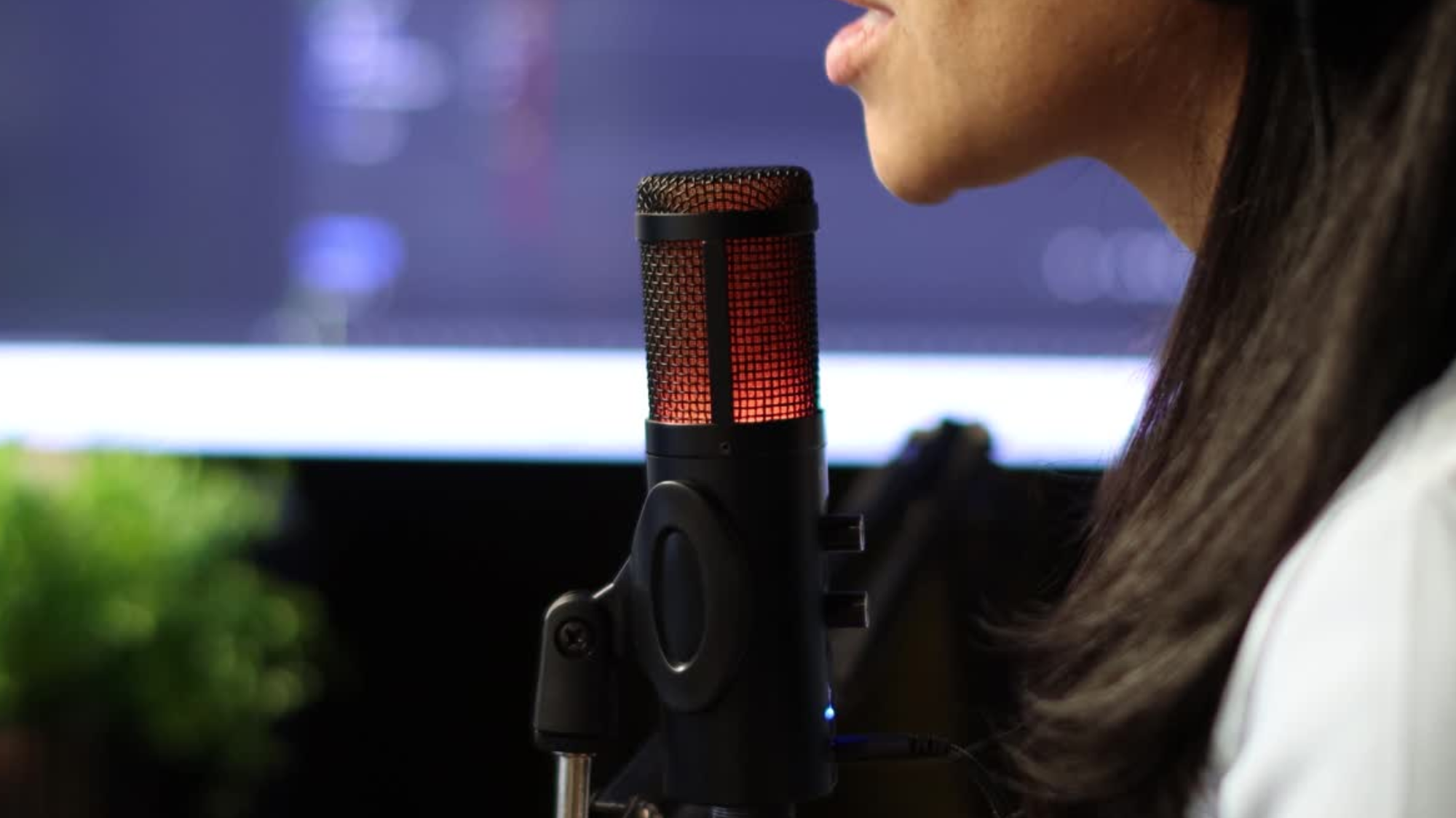 Close-up of a woman recording a podcast in a home studio. 
